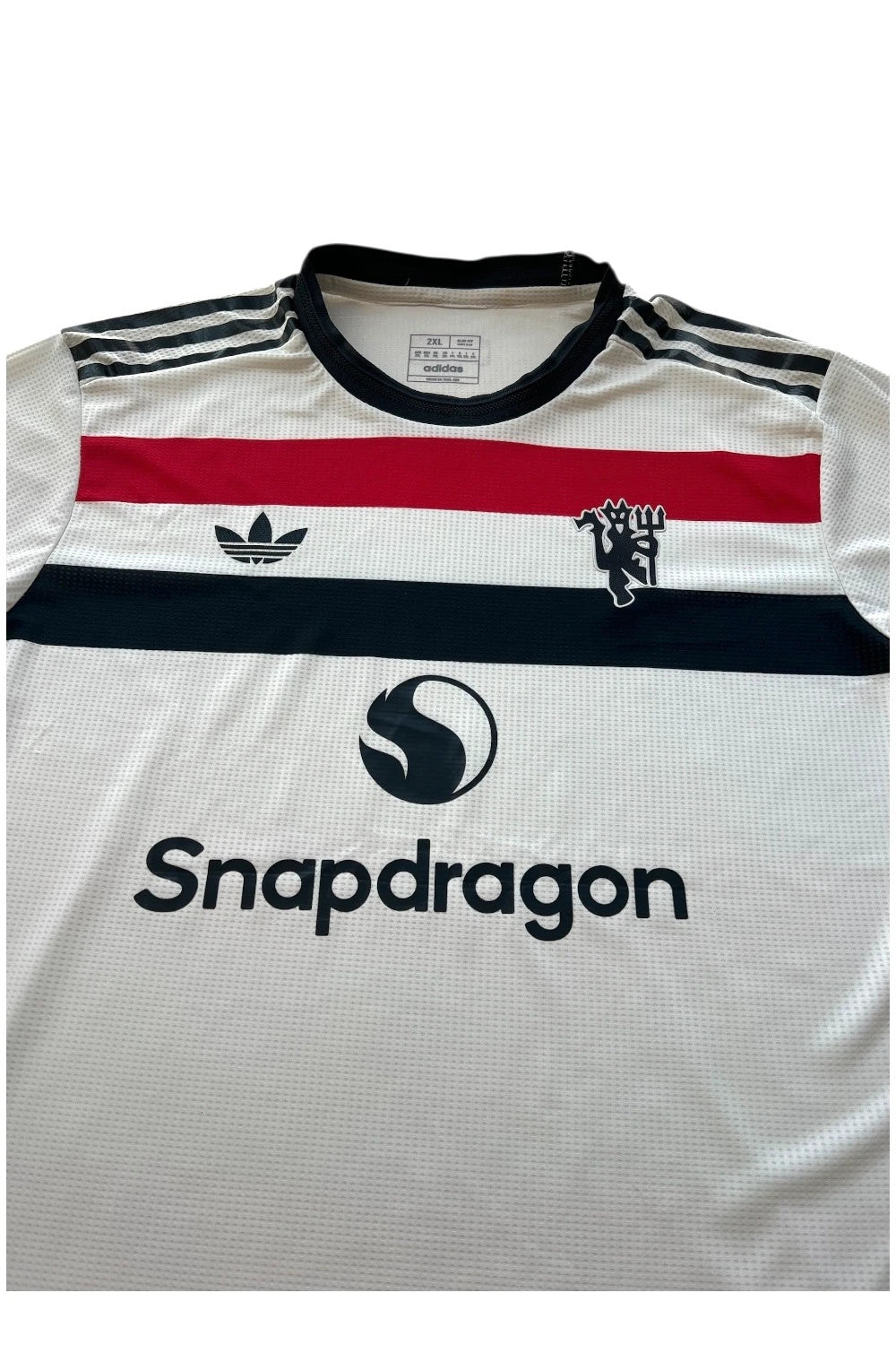 Adidas white graphic tee Manchester United logo, 100% polyester, sporty design.