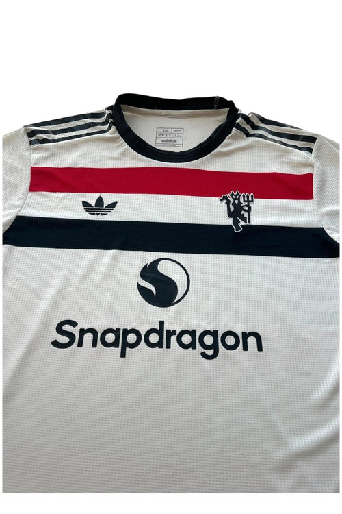 Adidas white graphic tee Manchester United logo, 100% polyester, sporty design.