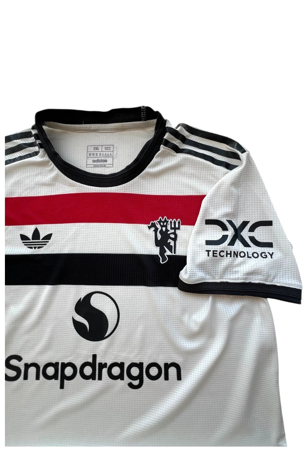 Adidas white graphic tee Manchester United logo, 100% polyester, sporty design.