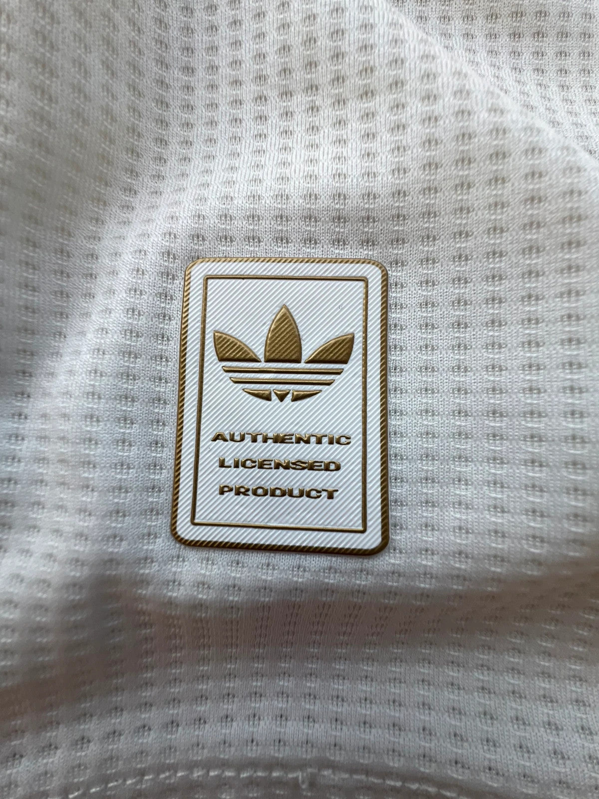 Adidas white graphic tee Manchester United logo, 100% polyester, sporty design.