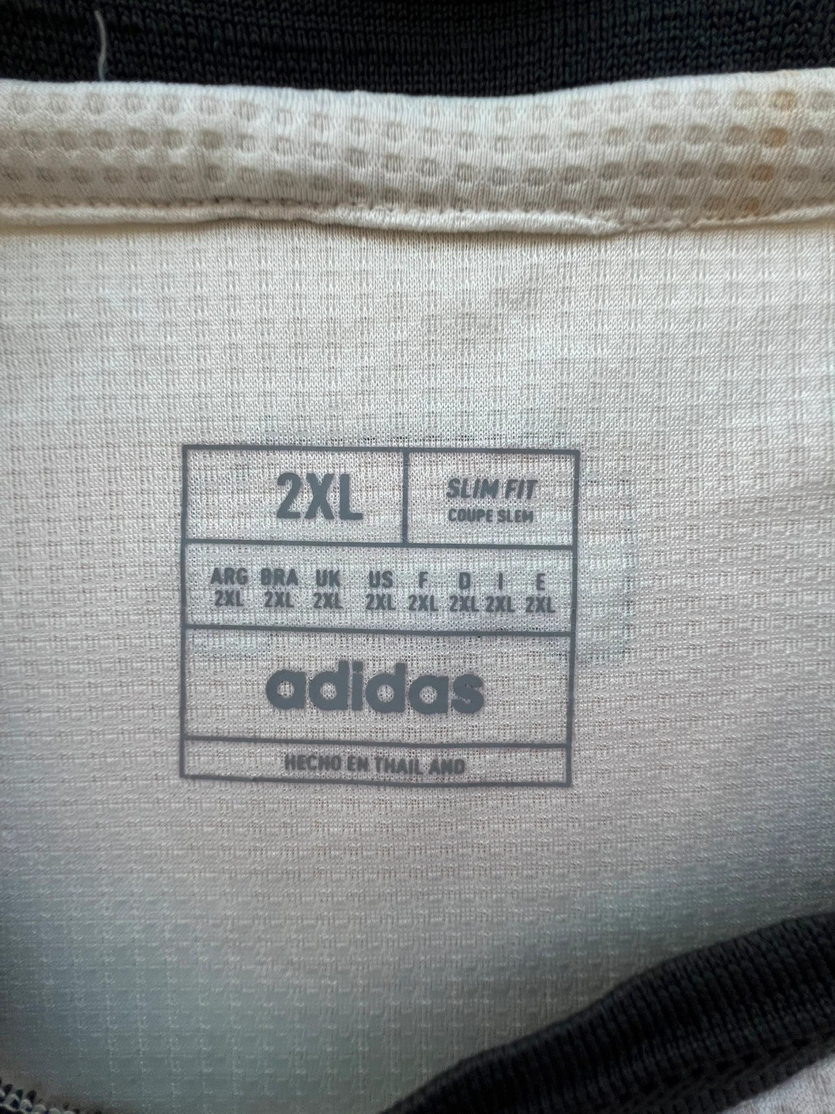 Adidas white graphic tee Manchester United logo, 100% polyester, sporty design.