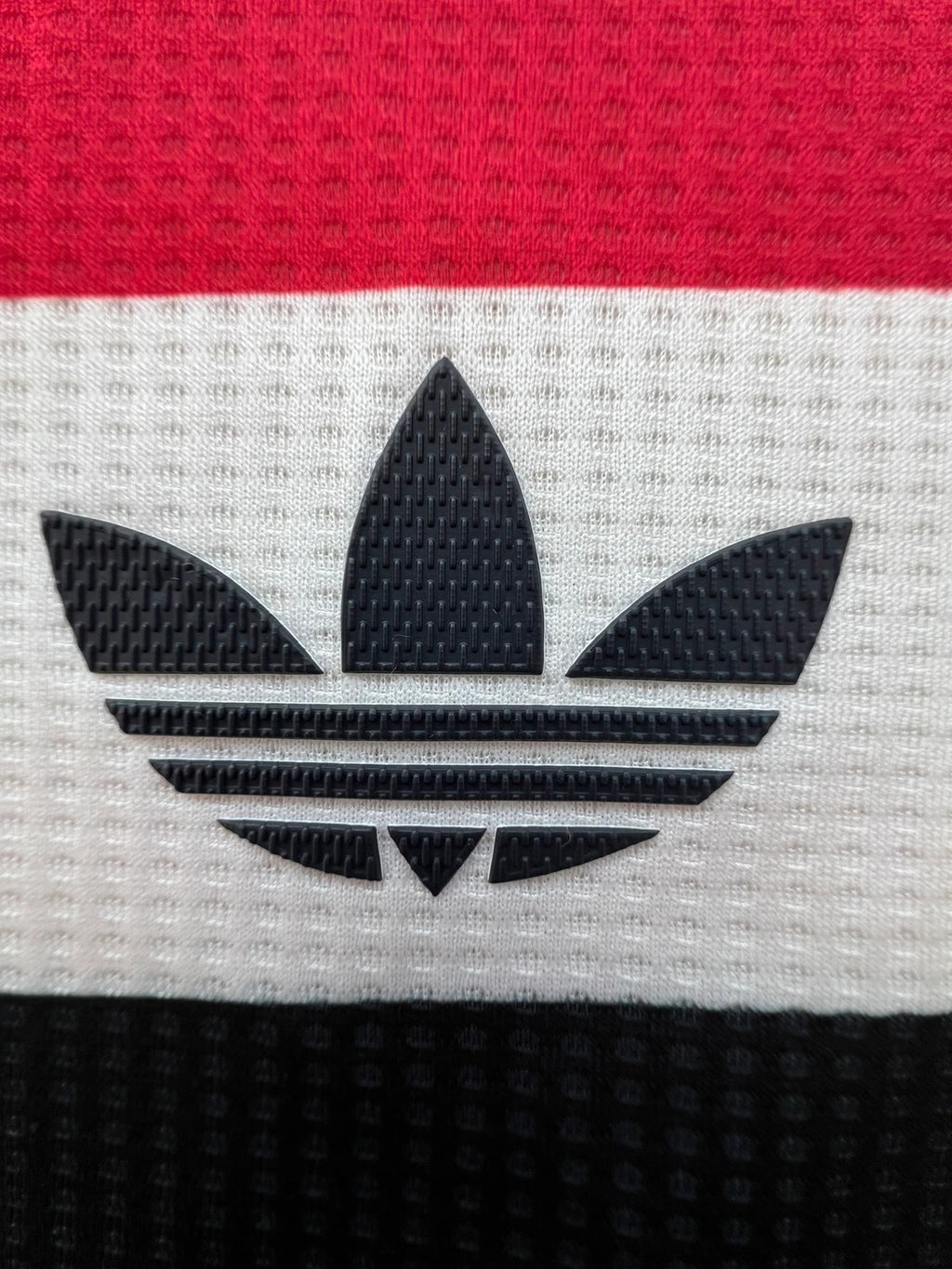 Adidas white graphic tee Manchester United logo, 100% polyester, sporty design.