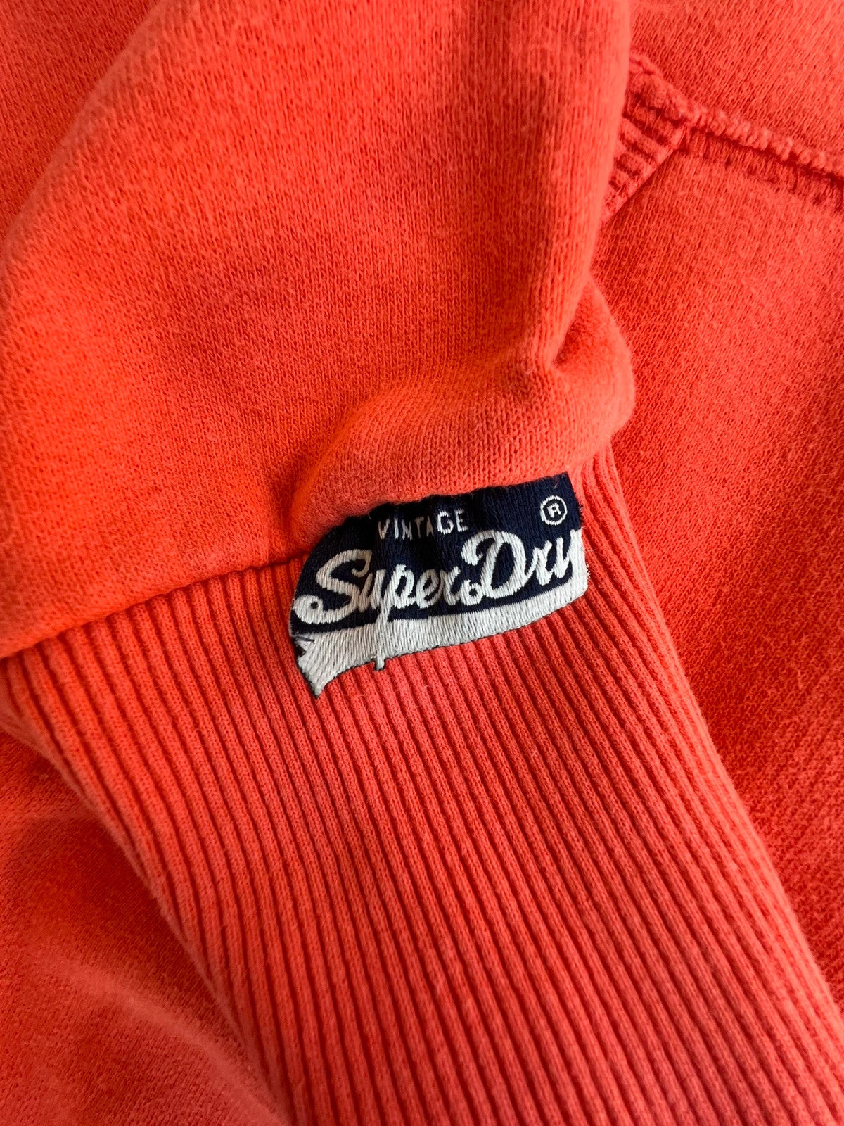 Superdry orange oversized hoodie with large vintage logo and casual streetwear style.