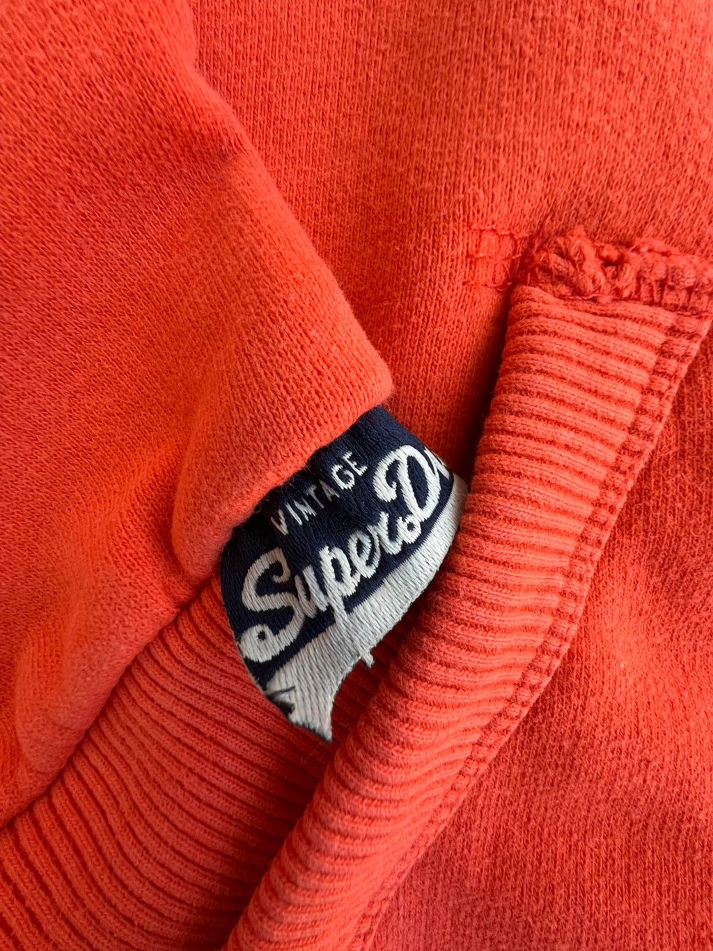 Superdry orange oversized hoodie with large vintage logo and casual streetwear style.