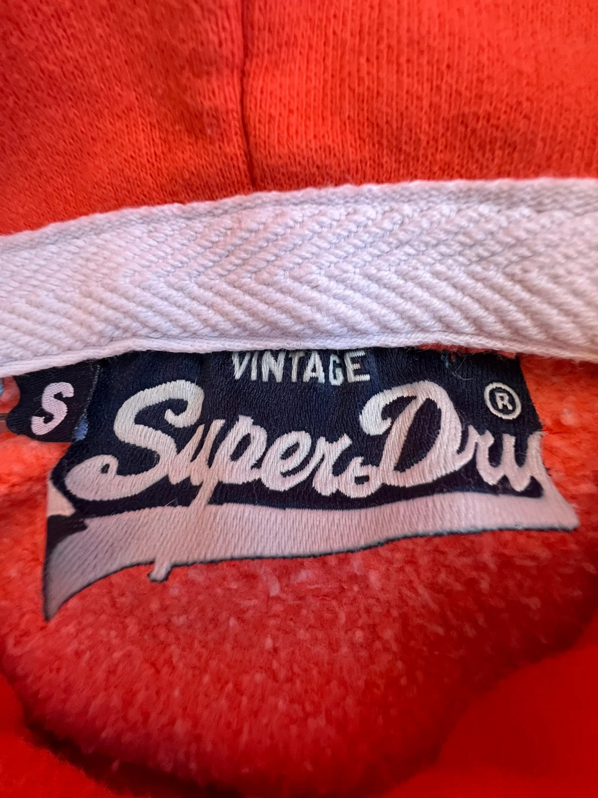 Superdry orange oversized hoodie with large vintage logo and casual streetwear style.