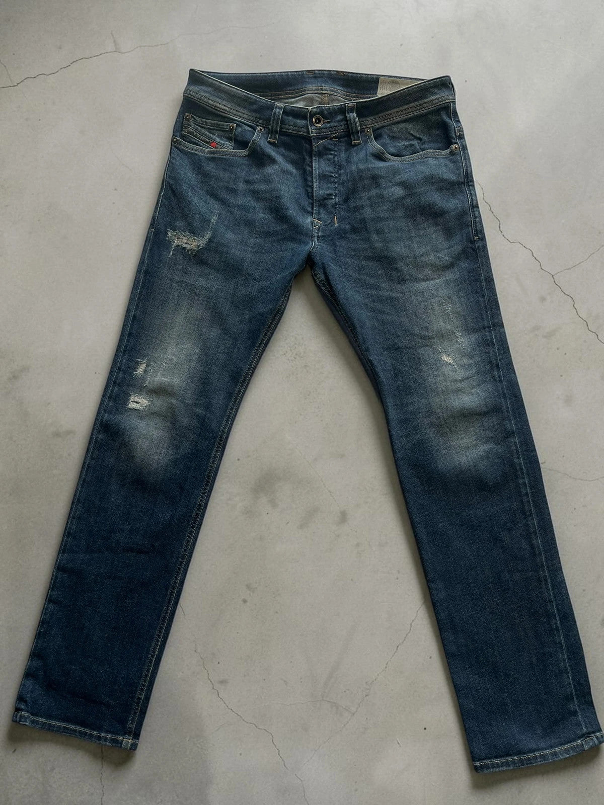 Diesel blue slim straight jeans with logo patch and classic denim texture.