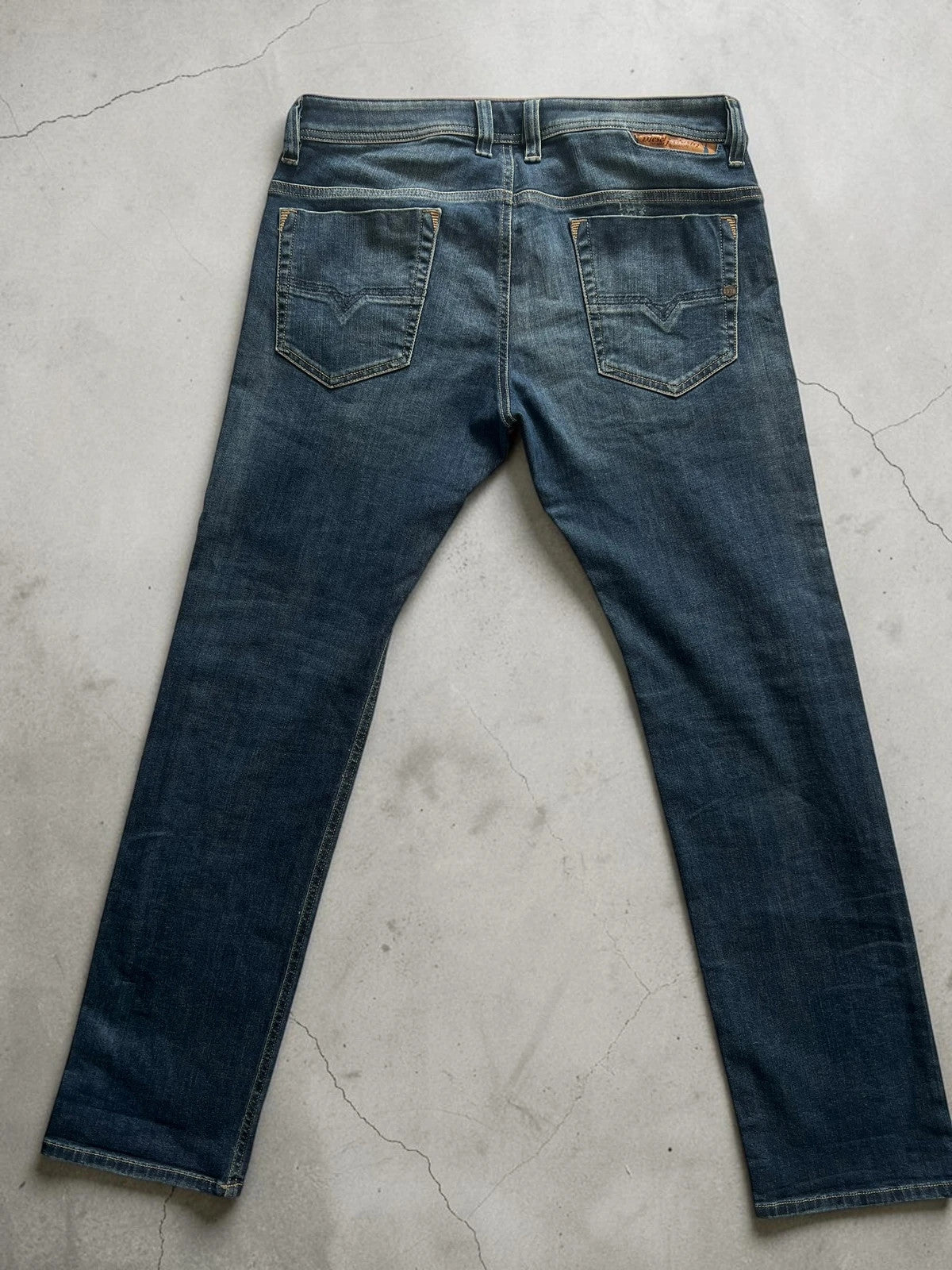Diesel blue slim straight jeans with logo patch and classic denim texture.