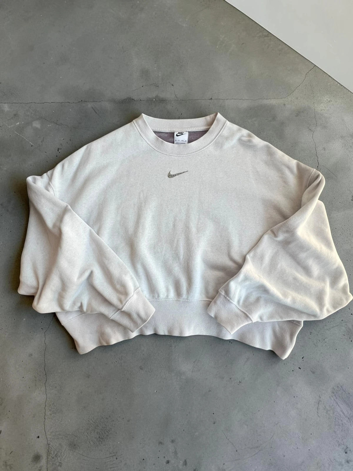 Nike cream cropped sweatshirt with embroidered mini swoosh logo, oversized fit.