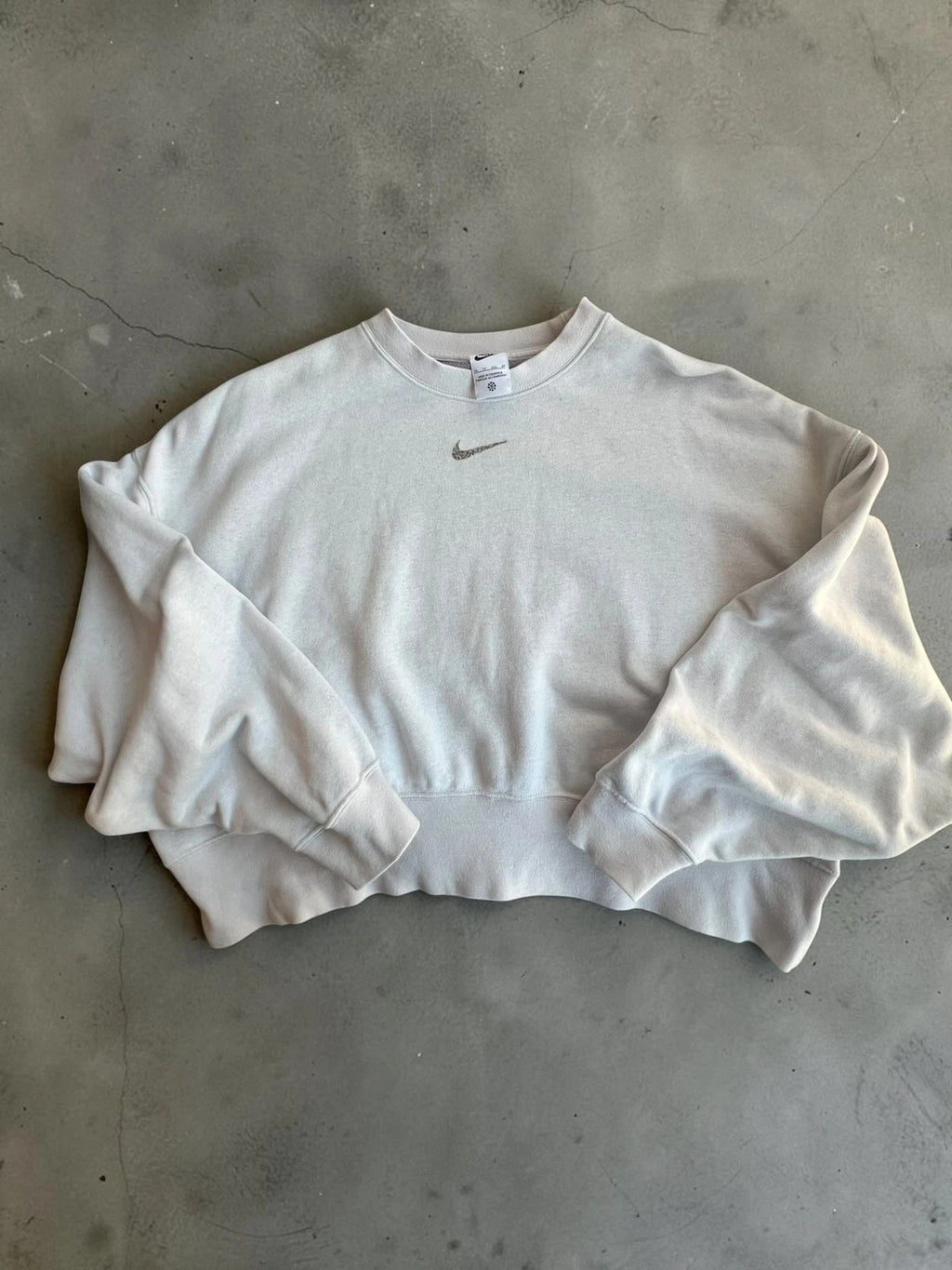 Nike cream cropped sweatshirt with embroidered mini swoosh logo, oversized fit.