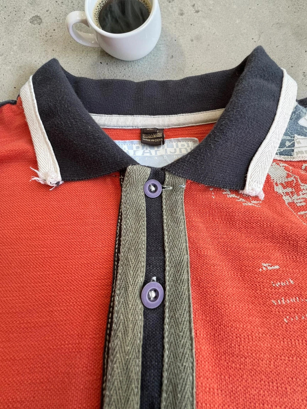 Napapijri orange long sleeve polo with embroidered patches and "Forever Wild and Free" graphic.