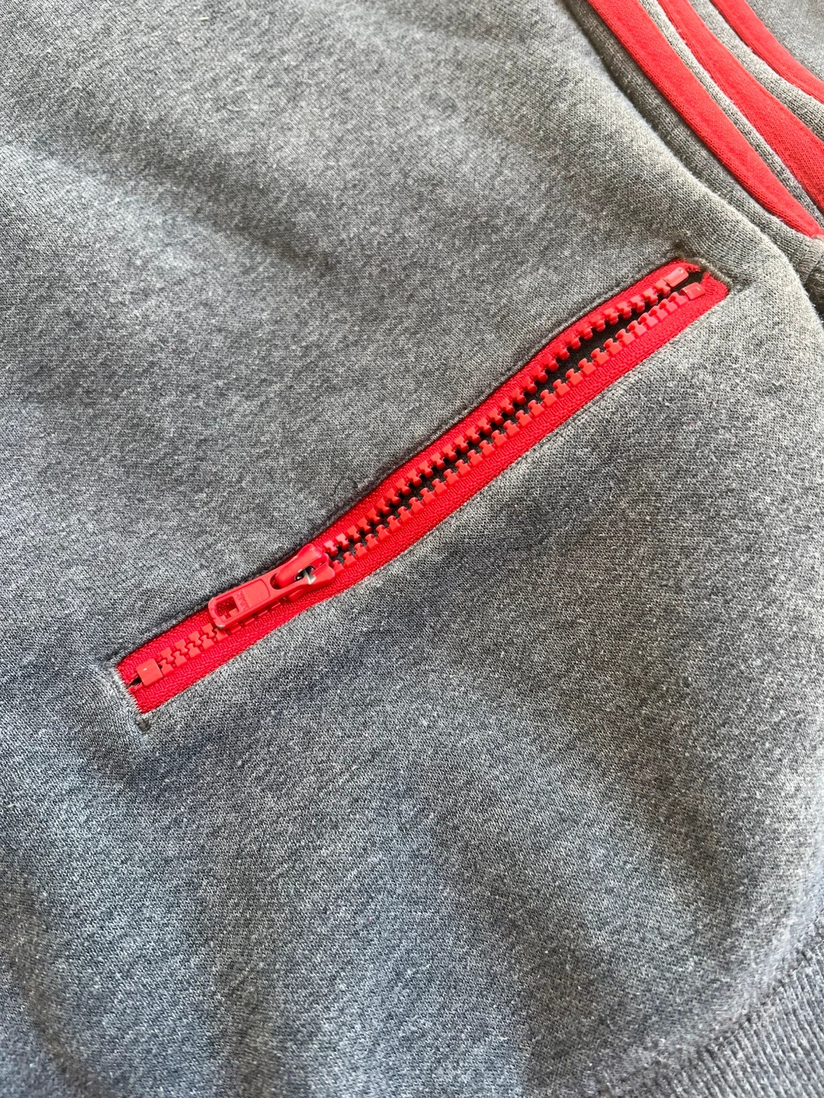 Adidas Originals grey sweatshirt with red details, embroidered Trefoil logo and decorative zipper.