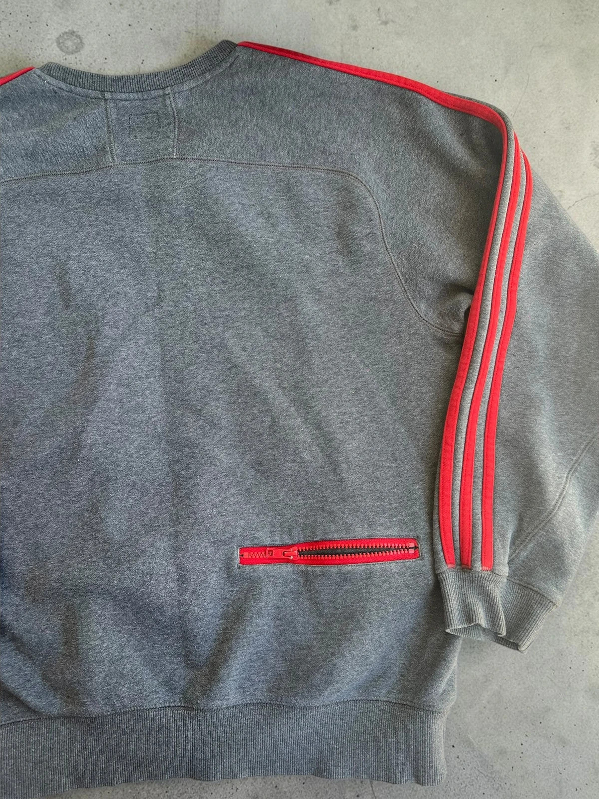 Adidas Originals grey sweatshirt with red details, embroidered Trefoil logo and decorative zipper.