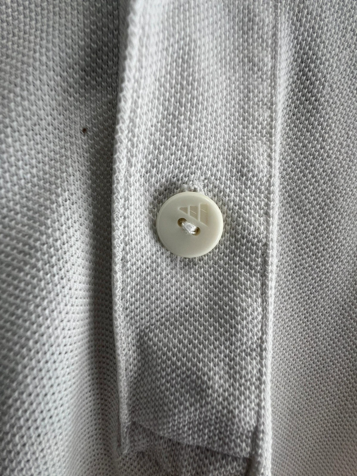 Adidas white polo shirt with embroidered blue logo, vintage Y2K style.