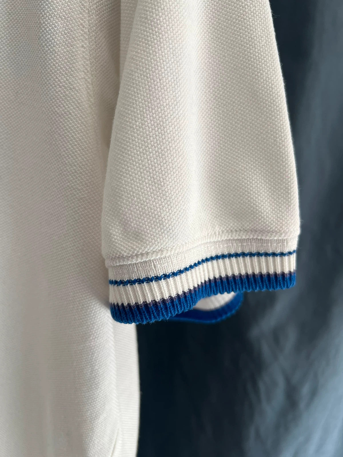 Adidas white polo shirt with embroidered blue logo, vintage Y2K style.