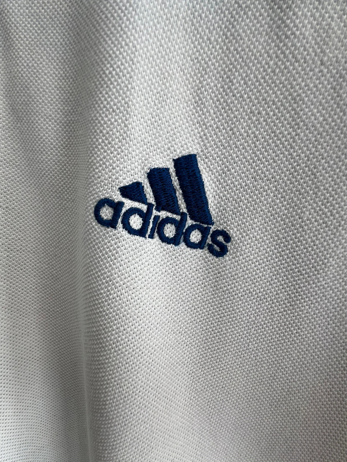 Adidas white polo shirt with embroidered blue logo, vintage Y2K style.
